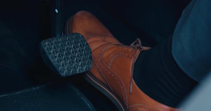 CU business man in brown leather shoes pressing the acceleration pedal in a modern car. 4K UHD