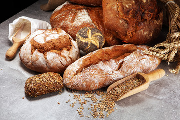Different kinds of bread and bread rolls on board from above. Kitchen or bakery