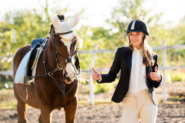 Girl equestrian rider stands near the horse. Horse farm
