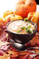 Roasted pumpkin and carrot soup with cream and pumpkin seeds on wooden background.