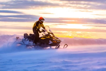 Fotobehang A man is ridind snowmobile in mountains. © Taras