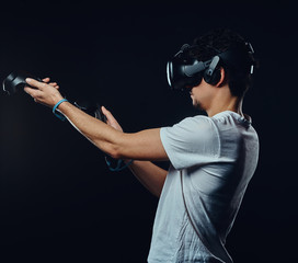 Side view of a man with bristle dressed in white shirt playing games with virtual reality goggles.