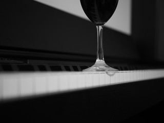 Glass of red wine on piano, black and white - 230520885
