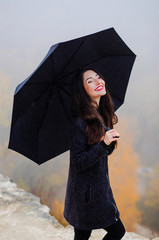 A wonderful girl with an umbrella in her hands stands in the rain