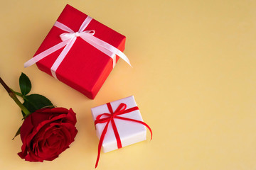 Red and white gift boxes with red rose on yellow background. Copy space.