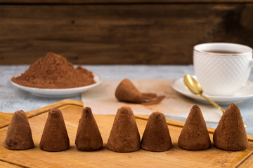 A number of chocolates sprinkled with cocoa powder, porcelain mug with tea on a saucer.