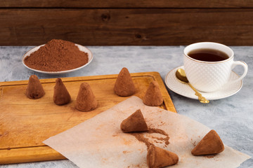 Home cooking - chocolate truffles in cocoa powder, white porcelain mug with tea.