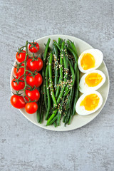 Fototapeta na wymiar A plate with a healthy meal. Green beans, boiled eggs, cherry tomatoes. Keto diet. Keto snack.