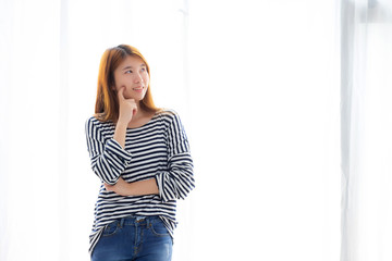 Beautiful portrait young asian woman confident thinking with curtain background, girl standing expression serious or doubts with idea, lifestyle concept.