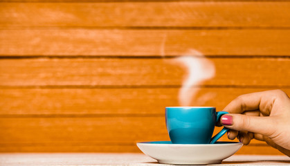blue cup of coffee or tea with steam on wooden background