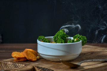 Hot and smoked mushroom cream soup on wooden background, selective focus. Copy text.
