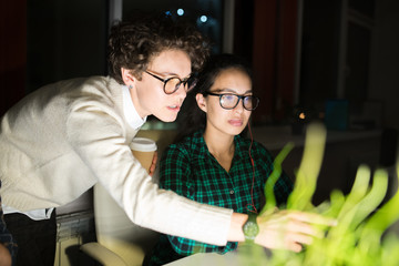 Portrait of female manager giving instructions to colleague while working in dark office late at...