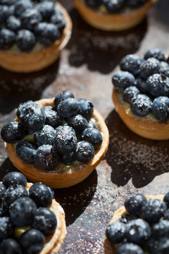 Blueberry tarts on dark background with powdered sugar