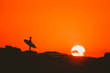 silhouette of man surfer on the background of sunset sky
