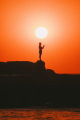 silhouette of man on top of rocks at the beach