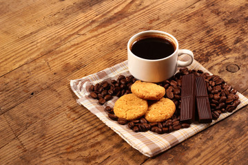 Cup of coffee, cookies and chocolate bars on wooden background