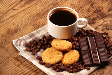 Cup of coffee, cookies and chocolate bars on wooden background
