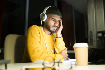 Portrait of exhausted Middle-Eastern man working late at night siting at desk  in dark office