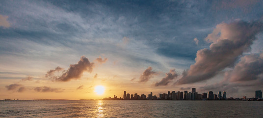 Skyline of downtown Miami viewed from the sea under sky and clouds at sunset, in Miami, Florida, USA