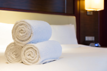 Three rolls of white bath towel on hotel bed