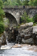 Fototapeta na wymiar Garve, Scotland: The Victorian-era Little Garve Bridge over Black Water, a river in the Scottish Highlands.