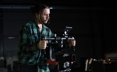 Professional videographer holding camera on 3-axis gimbal. Videographer using steadicam. Pro...