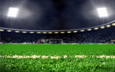 Empty  soccer field stadium with green grass and bright spotlights at night