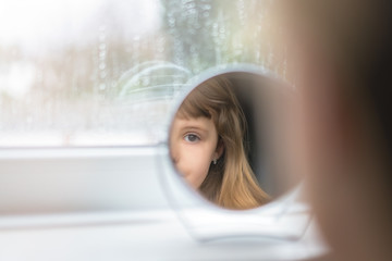 Little girl looking into the mirror