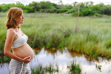 Pregnant woman relaxing looking at the landscape of a lake.