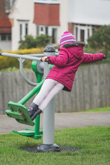 Little girl exercising on the outdoor training equipment