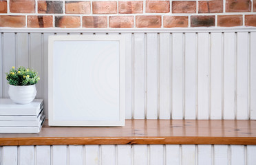 Mock up white wooden frame on wooden table with brick wall