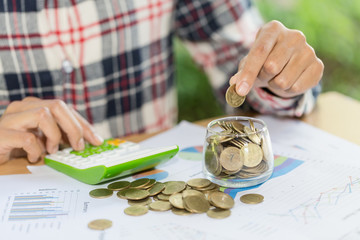 Woman's hand putting coin into glass of bottle for saving money, Saving money concept