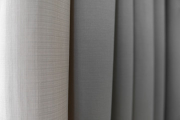 Fototapeta premium Close-up view of bright curtain in thin and thick vertical folds made of dense fabric.Textured abstract backgrounds and wallpapers.Materials and textiles.