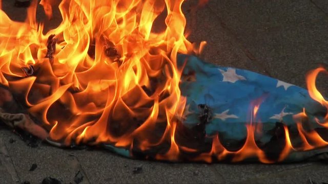 UK September 2012 - An American flag lies burning on the concrete floor.