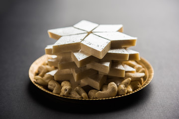 Kaju Katli is a Diamond shape Indian sweet made using cashew sugar and mava, served in a plate or bowl over moody background. selective focus