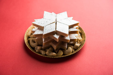 Kaju Katli is a Diamond shape Indian sweet made using cashew sugar and mava, served in a plate or bowl over moody background. selective focus