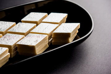 Kaju Katli is a Diamond shape Indian sweet made using cashew sugar and mava, served in a plate or bowl over moody background. selective focus