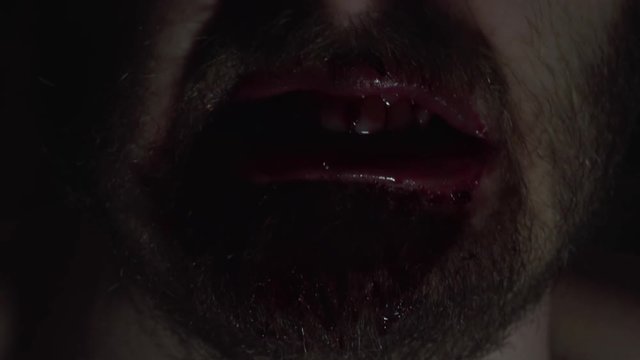 Creepy man zombie, cannibal furiously eating raw meat with frenzy. Blood drips from the mouth. Horror, halloween concept