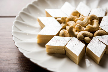 Kaju Katli is a Diamond shape Indian sweet made using cashew sugar and mava, served in a plate or bowl over moody background. selective focus