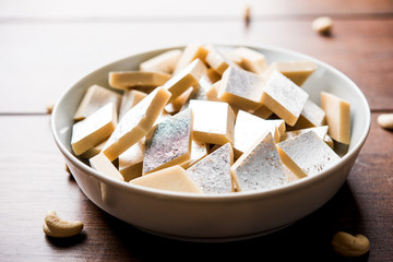Kaju Katli is a Diamond shape Indian sweet made using cashew sugar and mava, served in a plate or bowl over moody background. selective focus