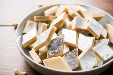 Kaju Katli is a Diamond shape Indian sweet made using cashew sugar and mava, served in a plate or bowl over moody background. selective focus
