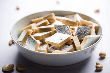 Kaju Katli is a Diamond shape Indian sweet made using cashew sugar and mava, served in a plate or bowl over moody background. selective focus