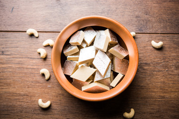 Kaju Katli is a Diamond shape Indian sweet made using cashew sugar and mava, served in a plate or bowl over moody background. selective focus