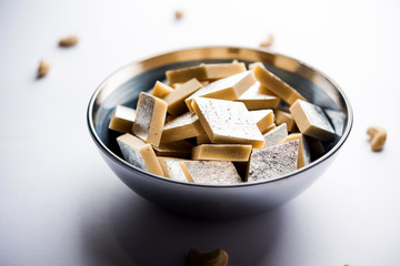 Kaju Katli is a Diamond shape Indian sweet made using cashew sugar and mava, served in a plate or bowl over moody background. selective focus