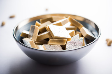 Kaju Katli is a Diamond shape Indian sweet made using cashew sugar and mava, served in a plate or bowl over moody background. selective focus