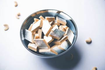 Kaju Katli is a Diamond shape Indian sweet made using cashew sugar and mava, served in a plate or bowl over moody background. selective focus