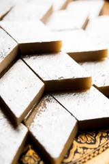 Kaju Katli is a Diamond shape Indian sweet made using cashew sugar and mava, served in a plate or bowl over moody background. selective focus