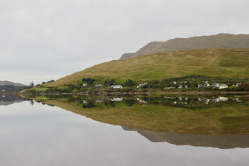 Still water shows a reflection of a valley landscape in the Connemara region of western Ireland
