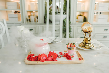 fruits cocktail and Panna cotta with rasperry and mint topping with strawberry sauce and rose petal on the white luxury table with a perfect fog from dry ice. Dessert Party