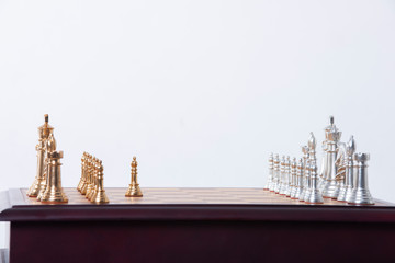 Gold and silver chess pieces on a wooden chess board